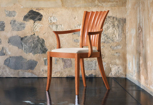Fauteuil - Les lignes sablier de son dossier unique se dessinent dans les courbes convexes et concaves sculptées à la main.