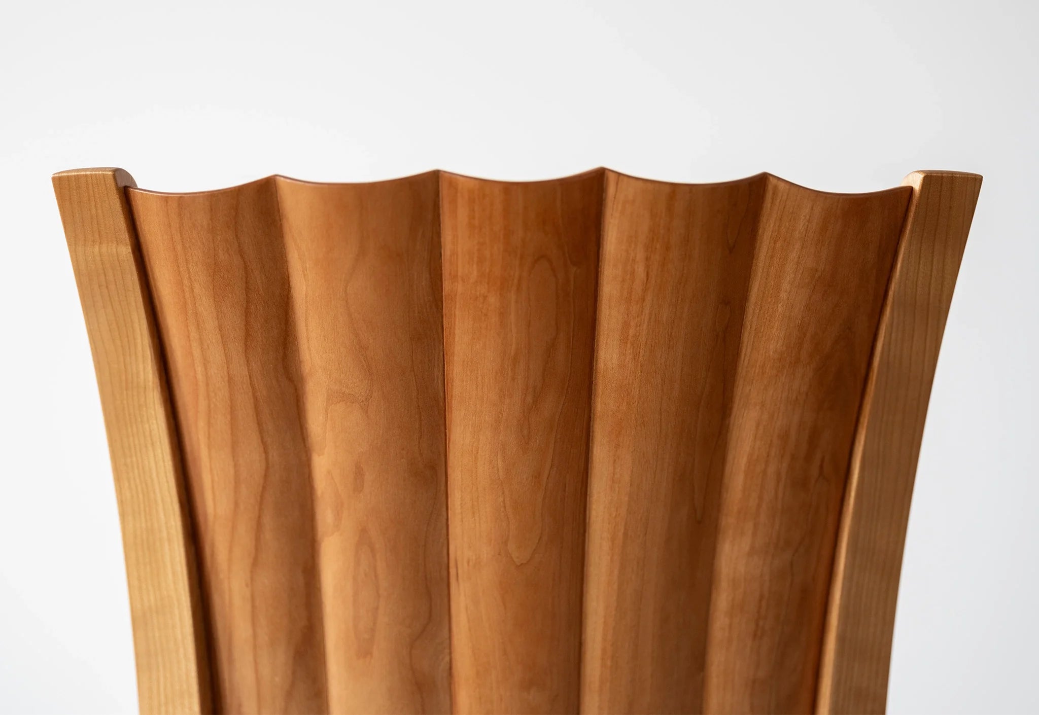 Fauteuil - Les lignes sablier de son dossier unique se dessinent dans les courbes convexes et concaves sculptées à la main.