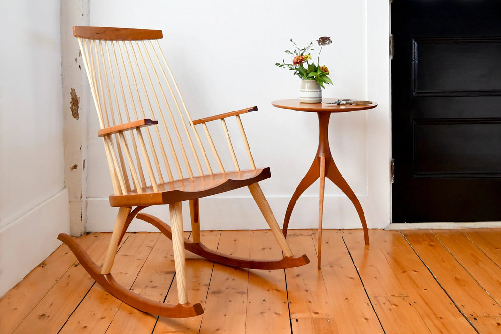 Table - Fabriquée en bois massif, finie à la main, la table est dotée de trois pieds qui s'arquent en s'élevant, formant une inverse