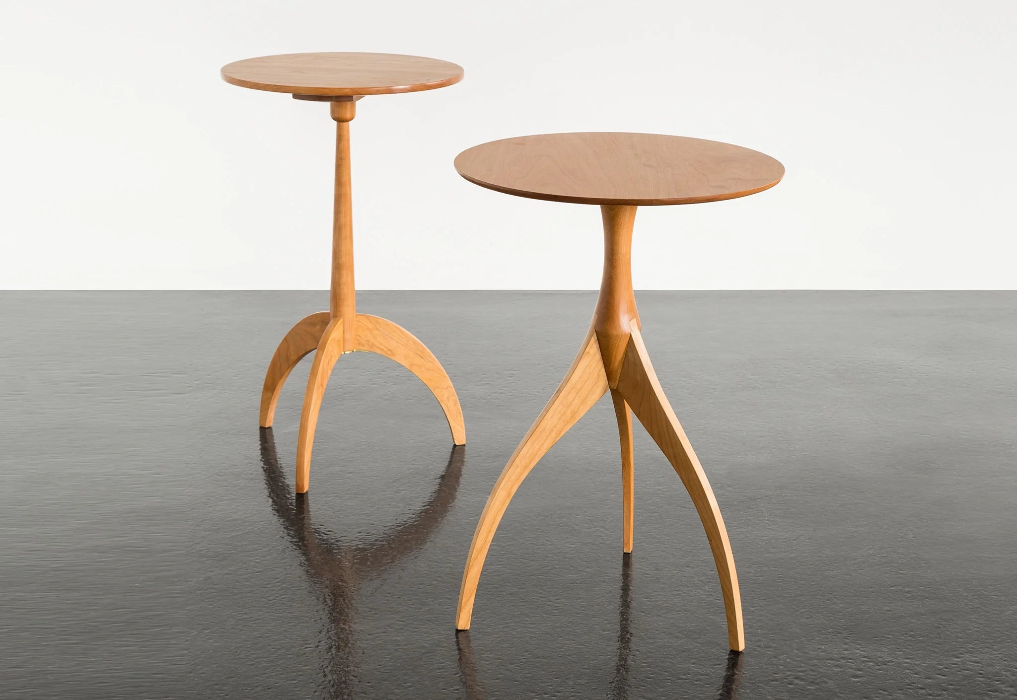 Table - Fabriquée en bois massif, finie à la main, la table est dotée de trois pieds qui s'arquent en s'élevant, formant une inverse