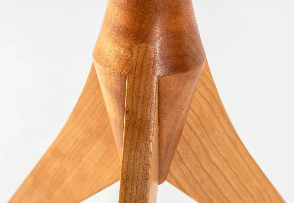 Table - Fabriquée en bois massif, finie à la main, la table est dotée de trois pieds qui s'arquent en s'élevant, formant une inverse