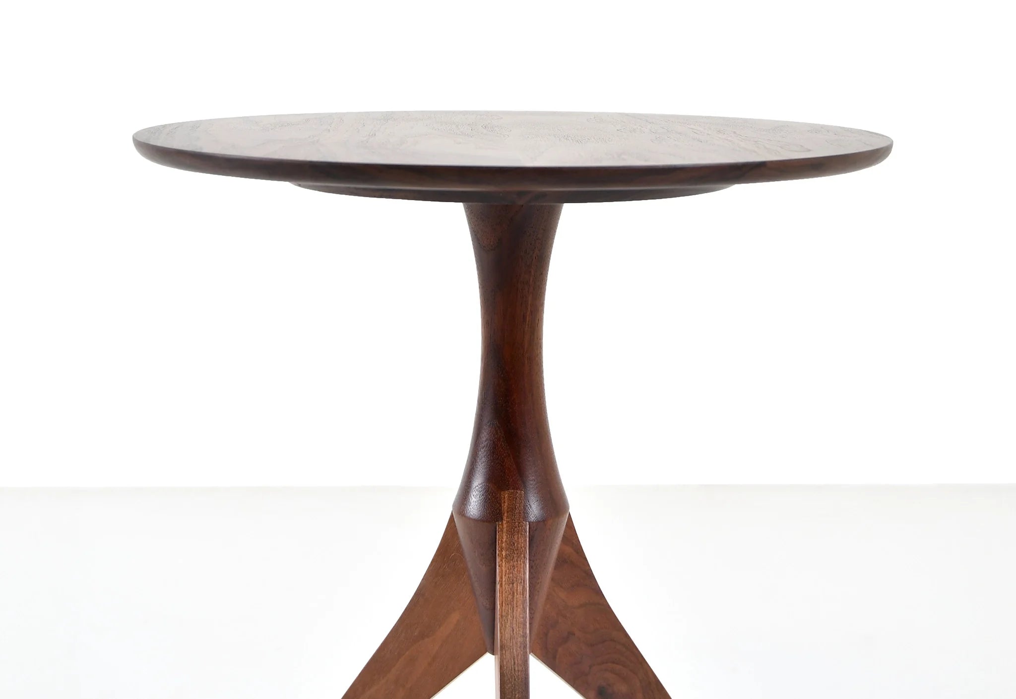 Table - Fabriquée en bois massif, finie à la main, la table est dotée de trois pieds qui s'arquent en s'élevant, formant une inverse