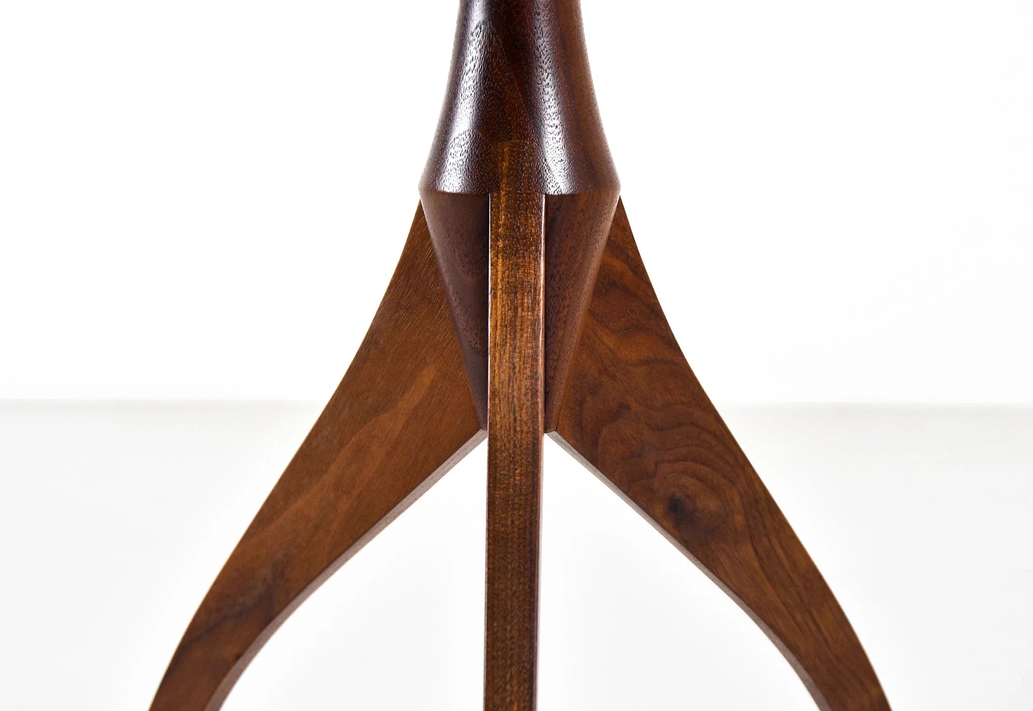 Table - Fabriquée en bois massif, finie à la main, la table est dotée de trois pieds qui s'arquent en s'élevant, formant une inverse