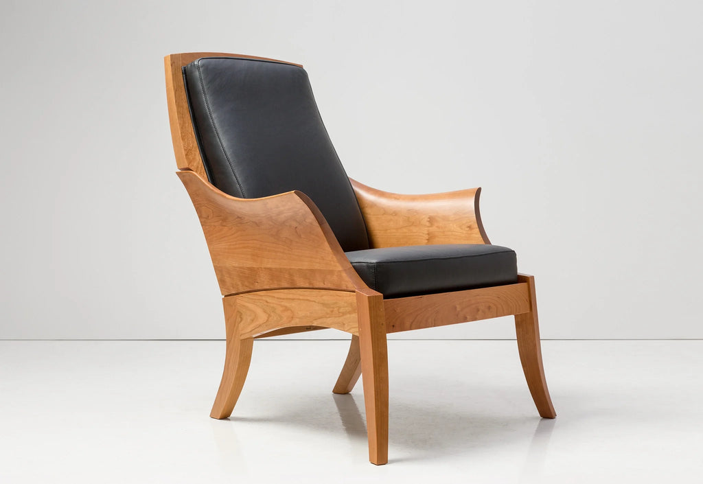 Chaise – Avec des accoudoirs incurvés sculptés dans des blocs de bois à grain assorti, la chaise tire ses origines d'un siège du XVIIIe siècle.